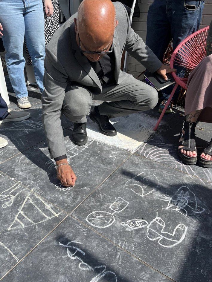 A visitor drawing with chalk on paving in the garden